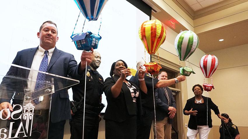 Principals of four Mobile County middle schools, accompanied by captains from partner police precincts, prepare to find out what order their schools will go in as the SOAR program is implemented. From left are Capt. Angela Prine, Booker T. Washington Middle School Principal Johnnie Williams, Katherine H. Hankins Middle School Principal Joshua Verkouille, Capt. Kevin Rogers (reaching for balloon), Palmer Pillans Middle School Principal Tammy George, Capt. Lee Laffitte and Bernice J. Causey Middle School Principal Jason Smith.Mike Kittrell/University of South Alabama